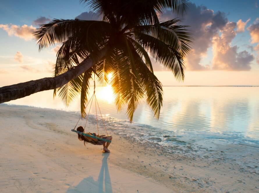 person swinging on hammock hanged on coconut tree near sea